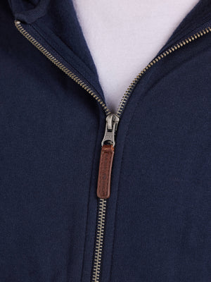 Close-up of a navy blue jacket with a zipper and leather pull tab on a white background