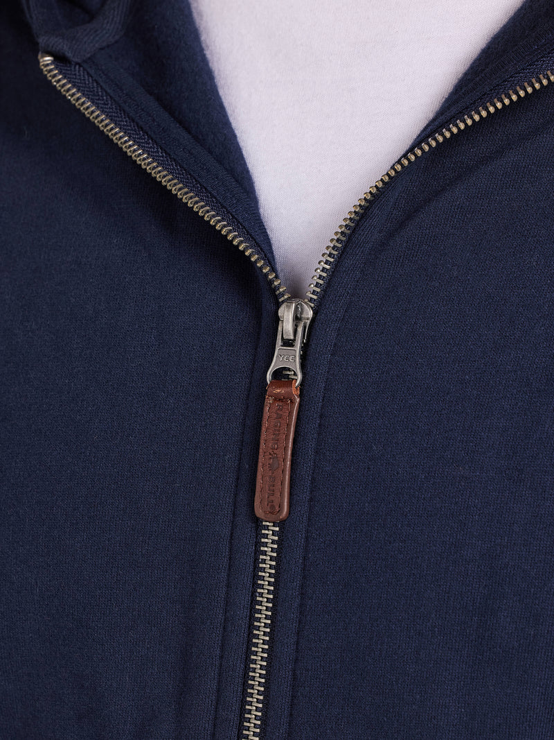 Close-up of a navy blue jacket with a zipper and leather pull tab on a white background
