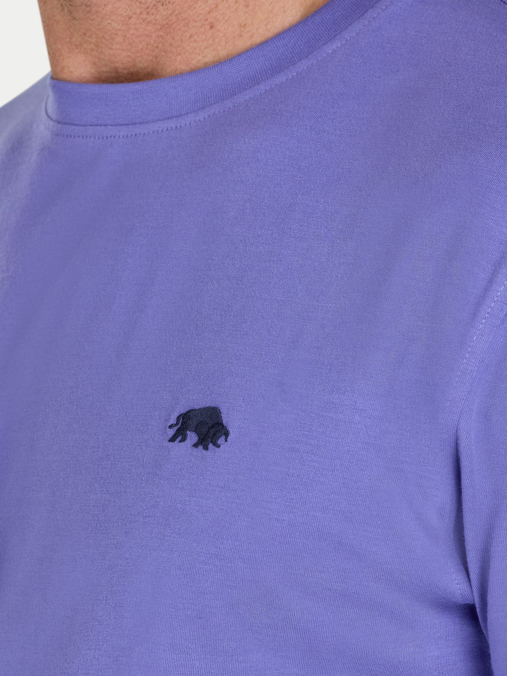 Close-up of a person wearing a purple t-shirt with a small black logo on the chest.