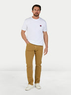 Man wearing a white t-shirt with a logo and beige pants on a white background