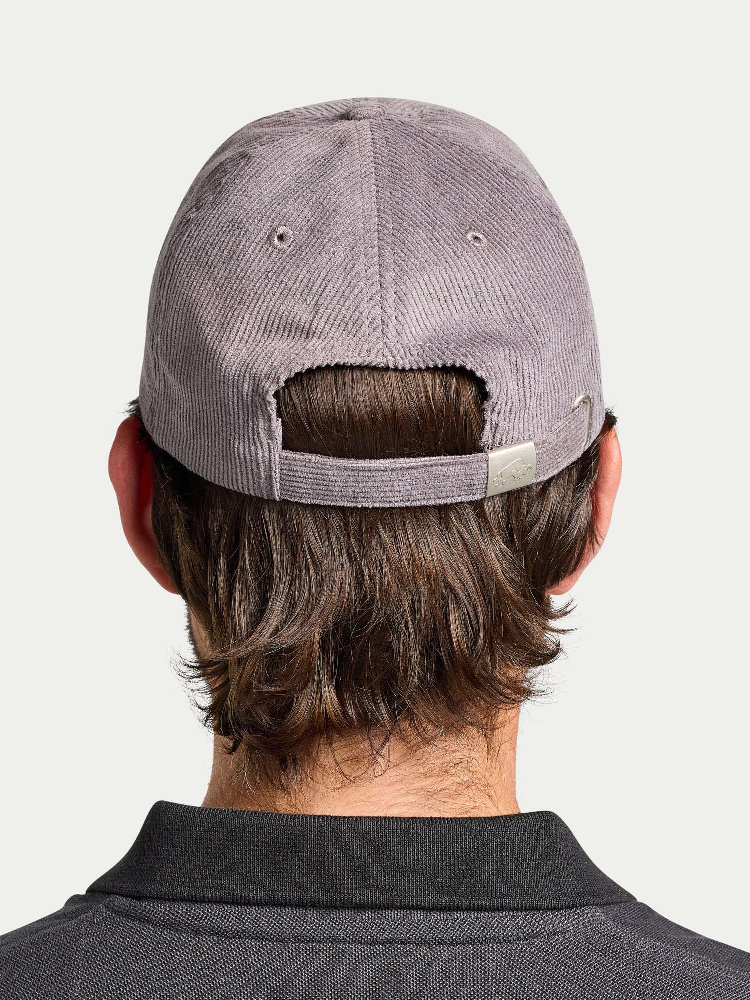 Person wearing a gray cap from behind on a light gray background