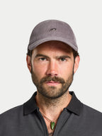 Man wearing a gray cap and dark shirt against a plain background