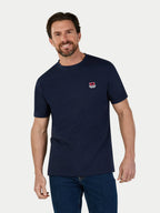 Man wearing a navy blue t-shirt with a small logo on a light gray background