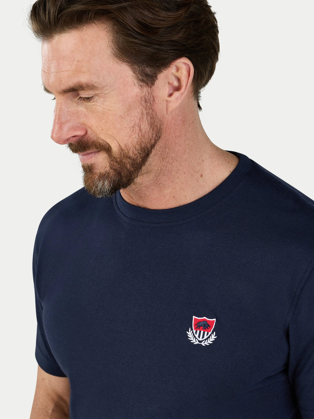 Man wearing a navy blue t-shirt with a logo on a white background
