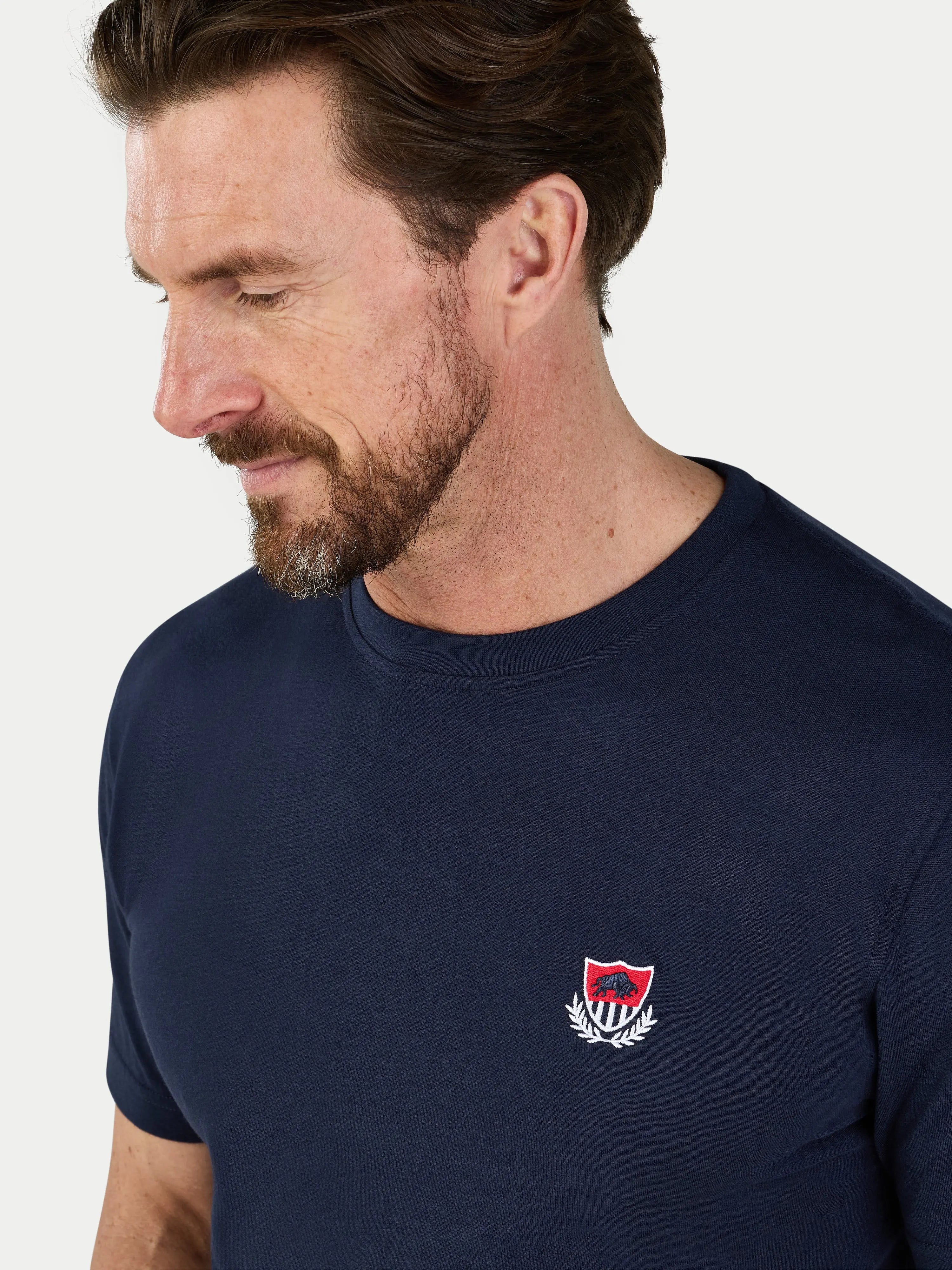 Man wearing a navy blue t-shirt with a logo on a white background