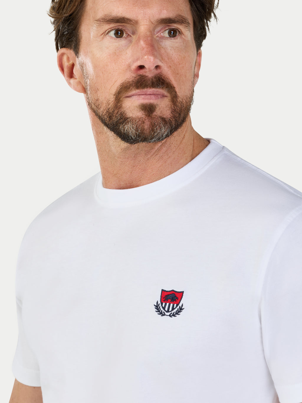 Man wearing a white t-shirt with a logo on a white background