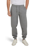 A man wearing light grey cuffed sweatpants with a drawstring waist, standing with hands in pockets and white sneakers on feet.