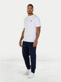 Man wearing a white t-shirt and navy jogger pants on a white background