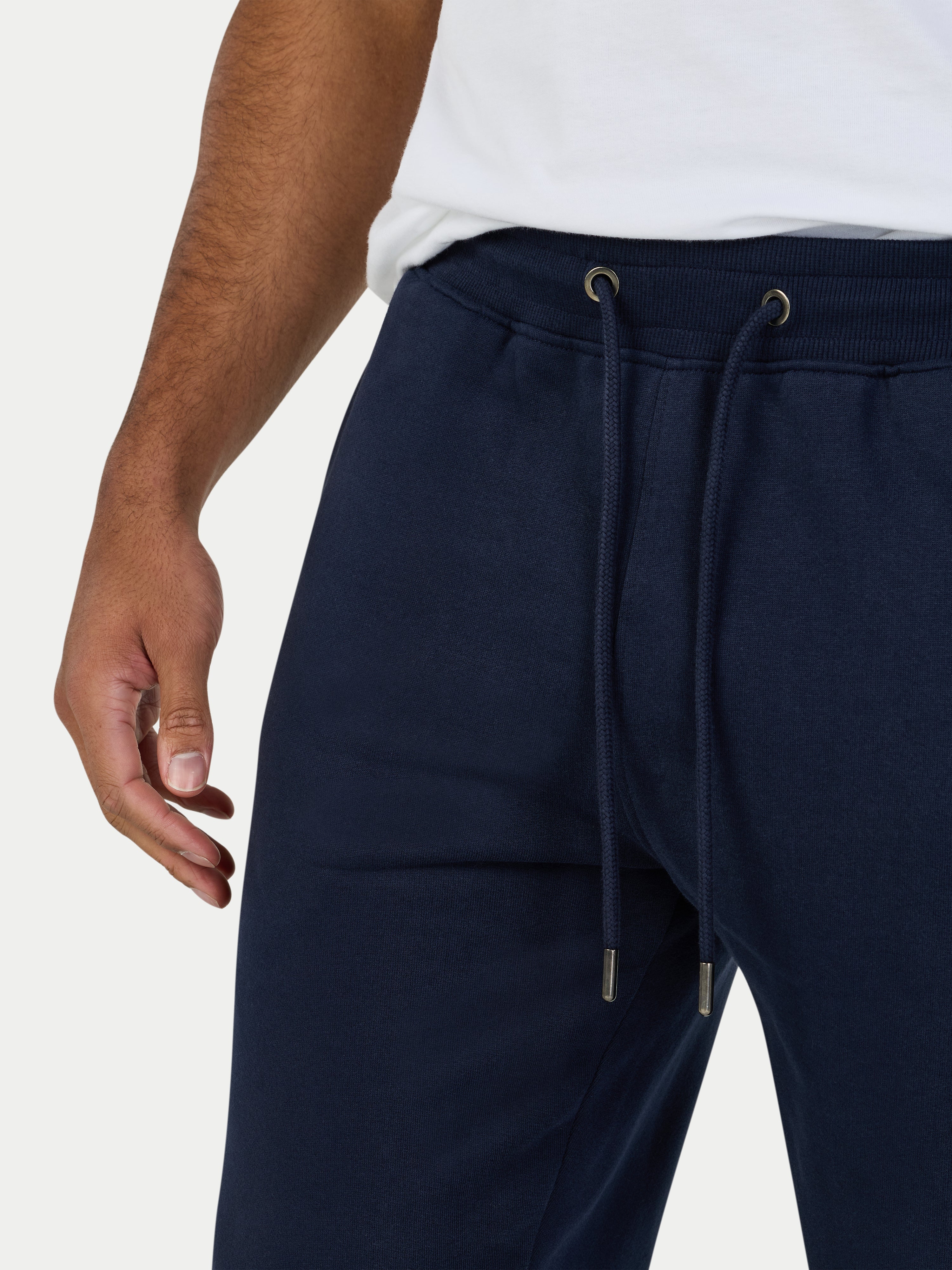 Navy blue jogger pants with a white shirt on a light gray background