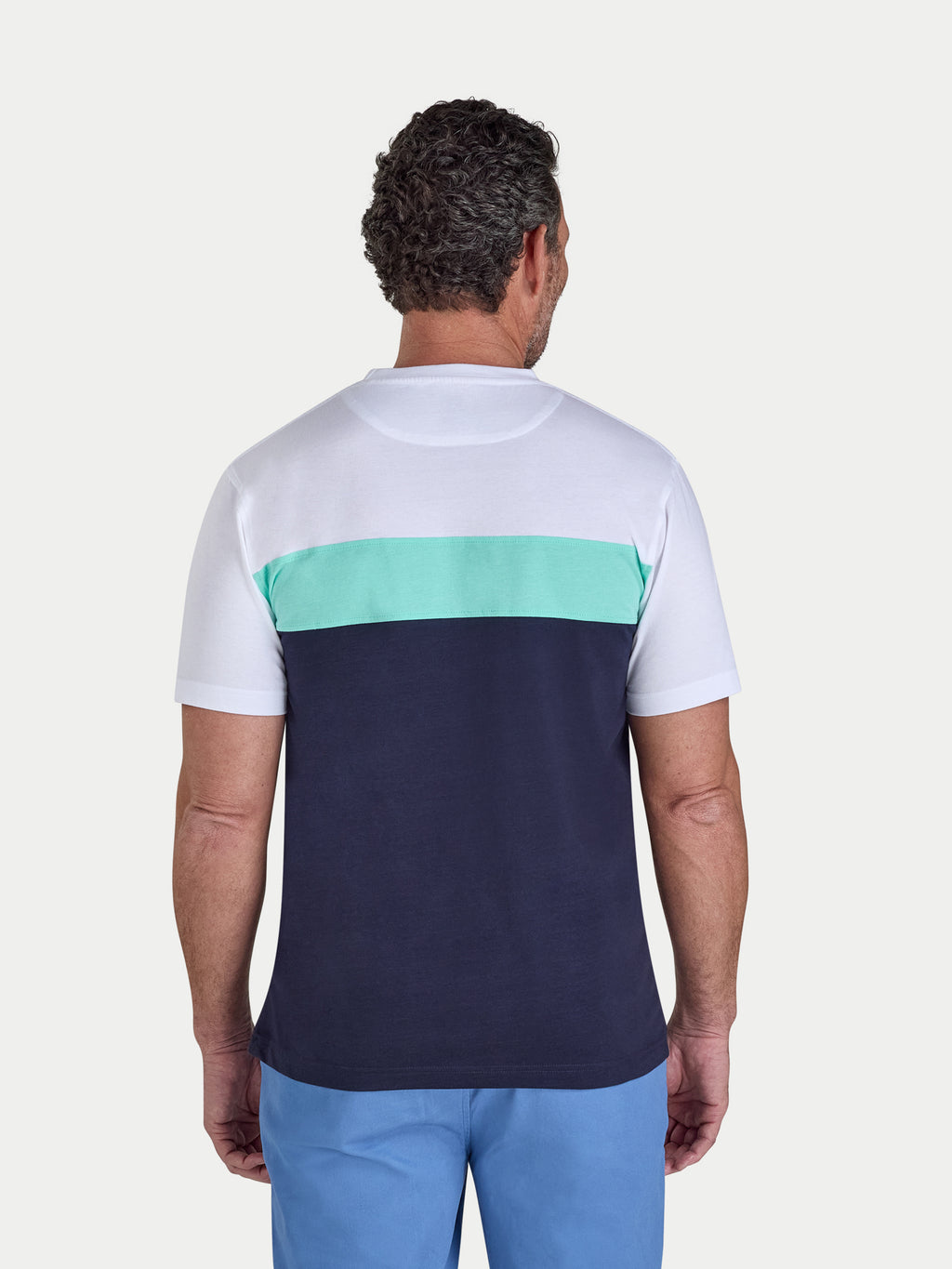 Man wearing a white and navy blue color-blocked t-shirt with a green stripe on a light gray background.