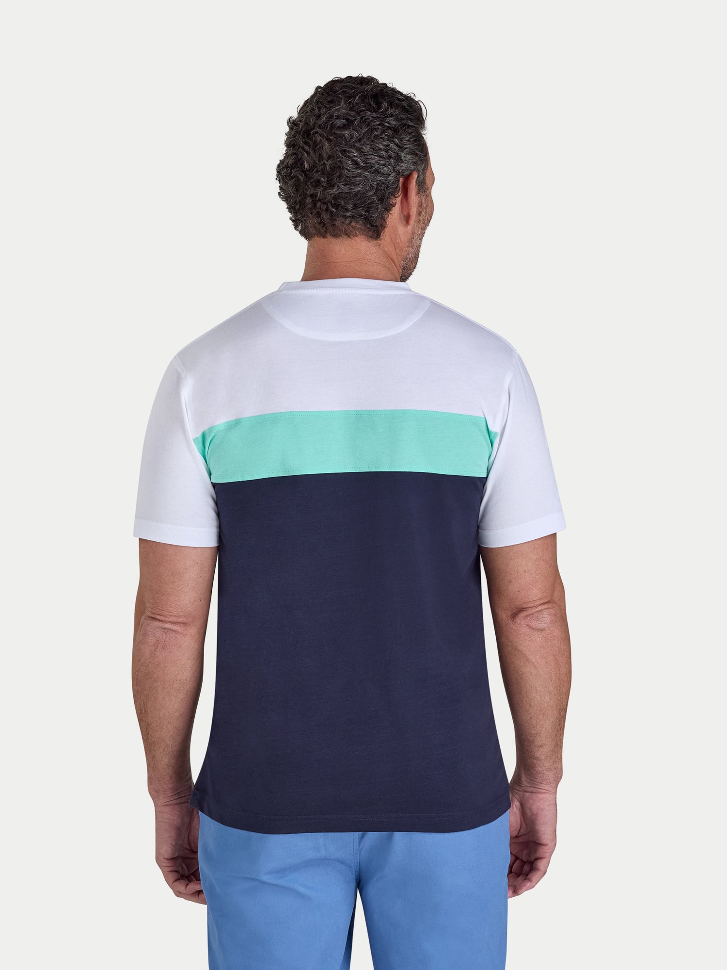 Man wearing a white and navy blue color-blocked t-shirt with a green stripe on a light gray background.