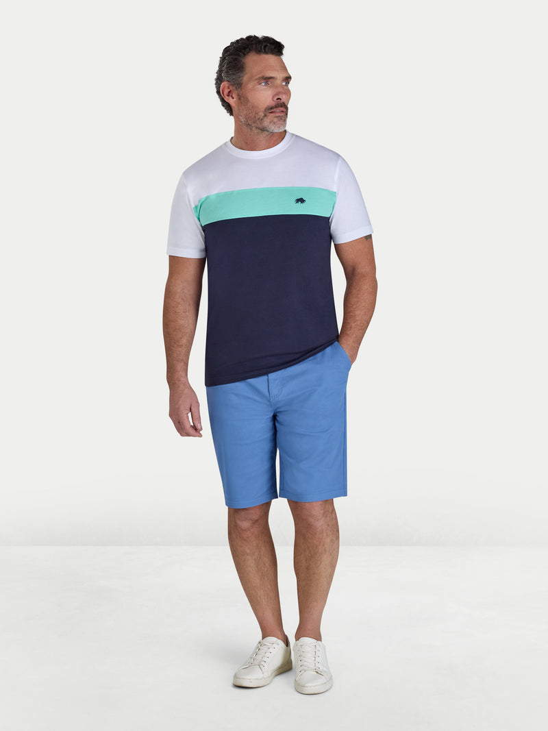 Man wearing a color-blocked t-shirt and blue shorts on a white background