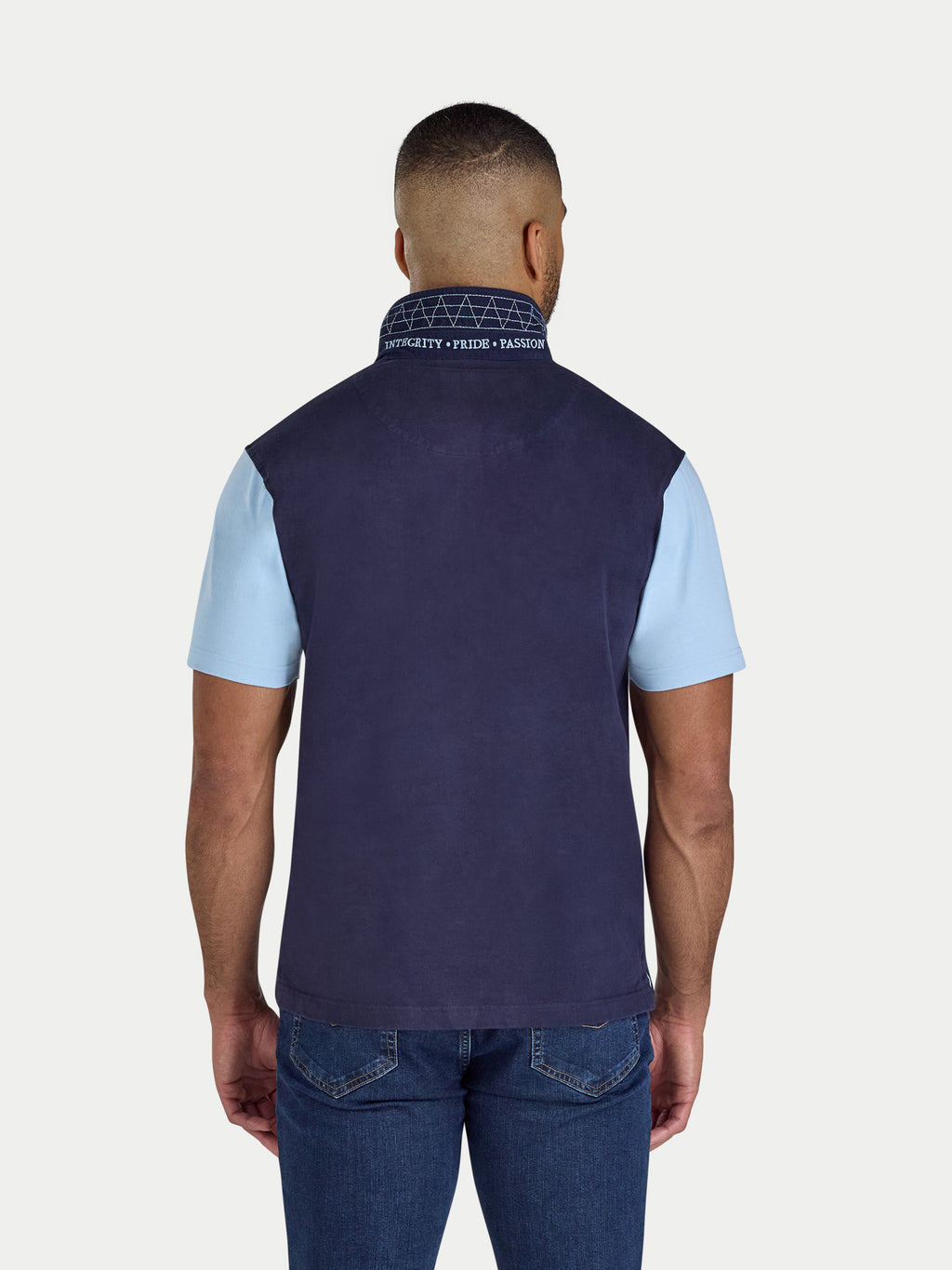 Man wearing a navy vest over a light blue shirt on a white background