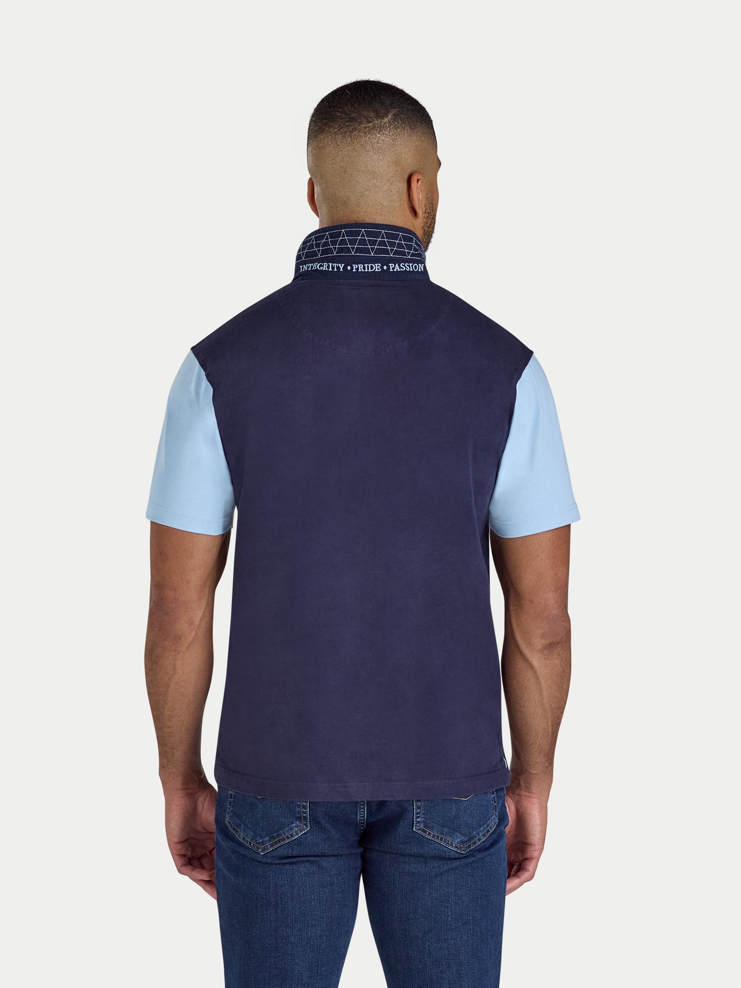 Man wearing a navy vest over a light blue shirt on a white background