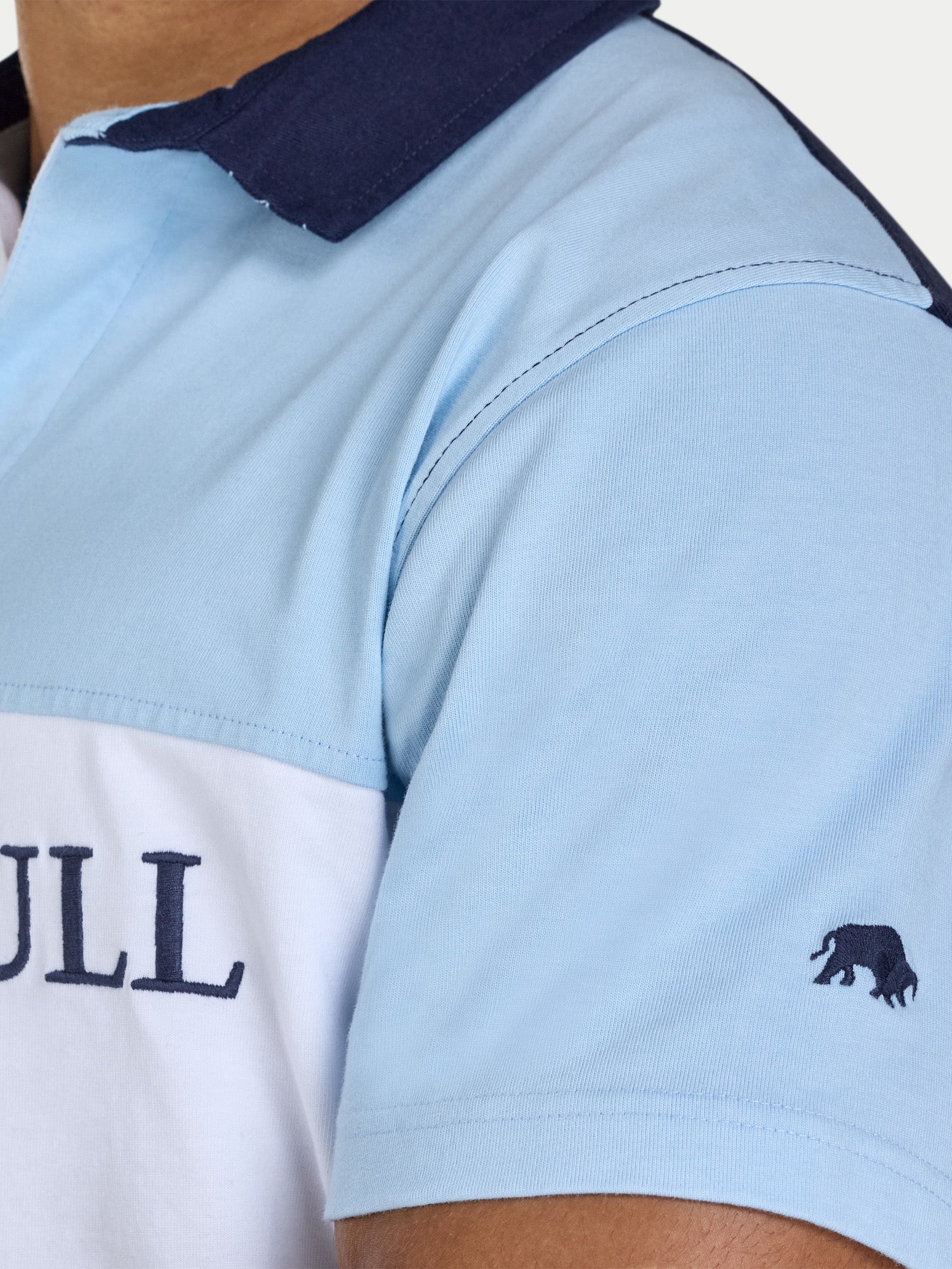 Close-up of a light blue and white polo shirt with a brand logo on a white background