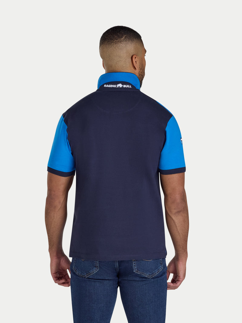 Man wearing a navy and blue polo shirt with a visible brand logo on the back.