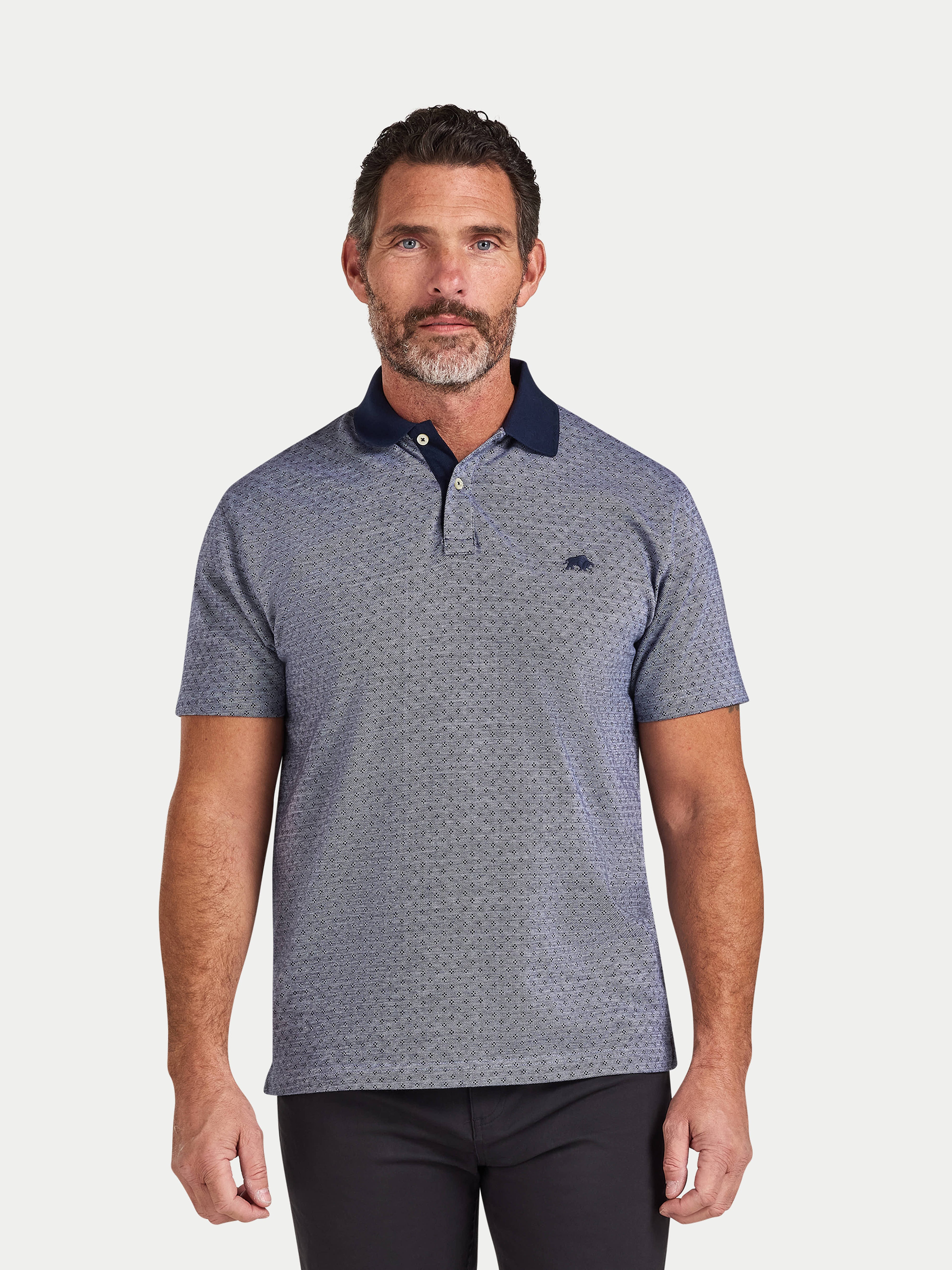 Man wearing a patterned polo shirt with a visible brand logo on a white background