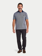 Man wearing a gray patterned polo shirt and black pants on a white background
