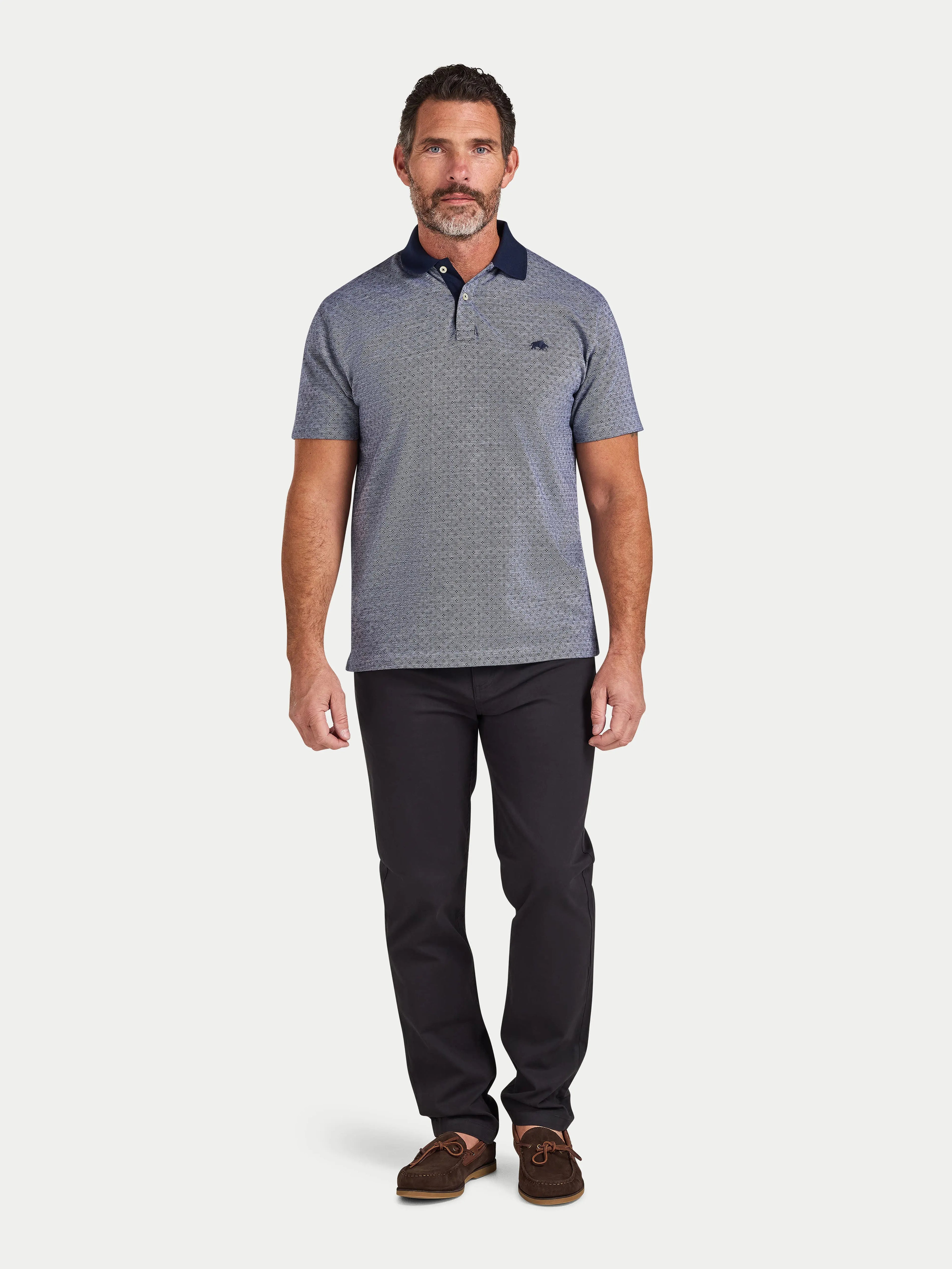 Man wearing a gray patterned polo shirt and black pants on a white background