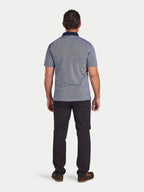 Man wearing a patterned polo shirt and dark pants on a white background