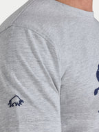 Gray t-shirt with a small logo on the sleeve against a white background
