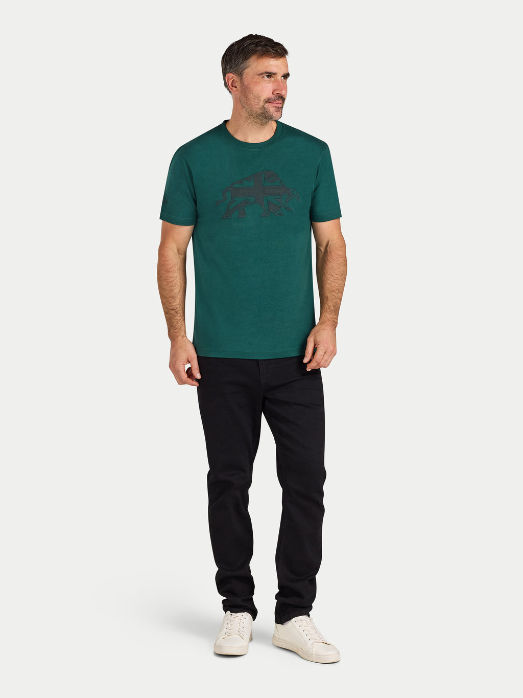 Man wearing a green t-shirt with a logo and black pants on a white background