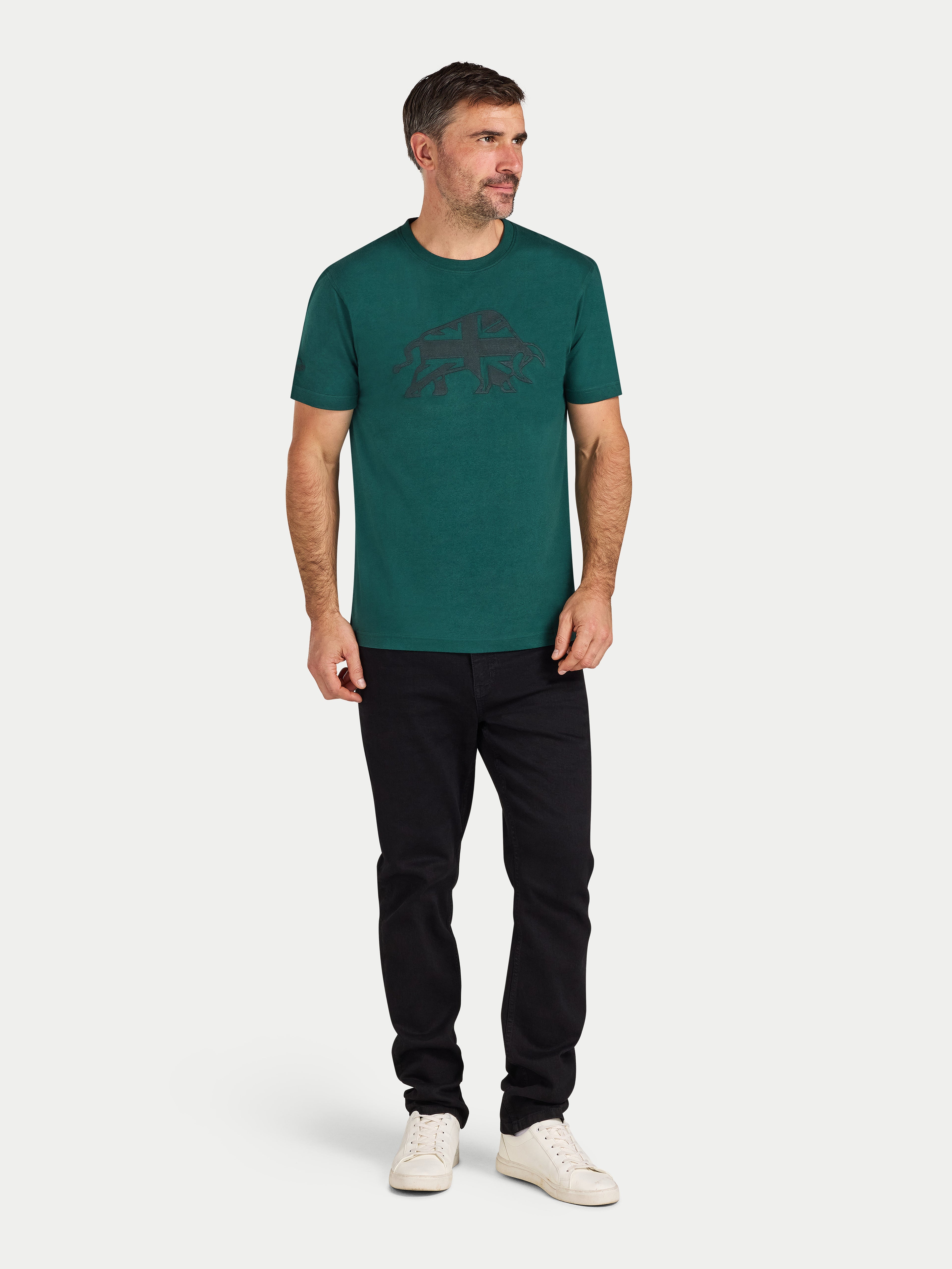 Man wearing a green t-shirt with a logo and black pants on a white background