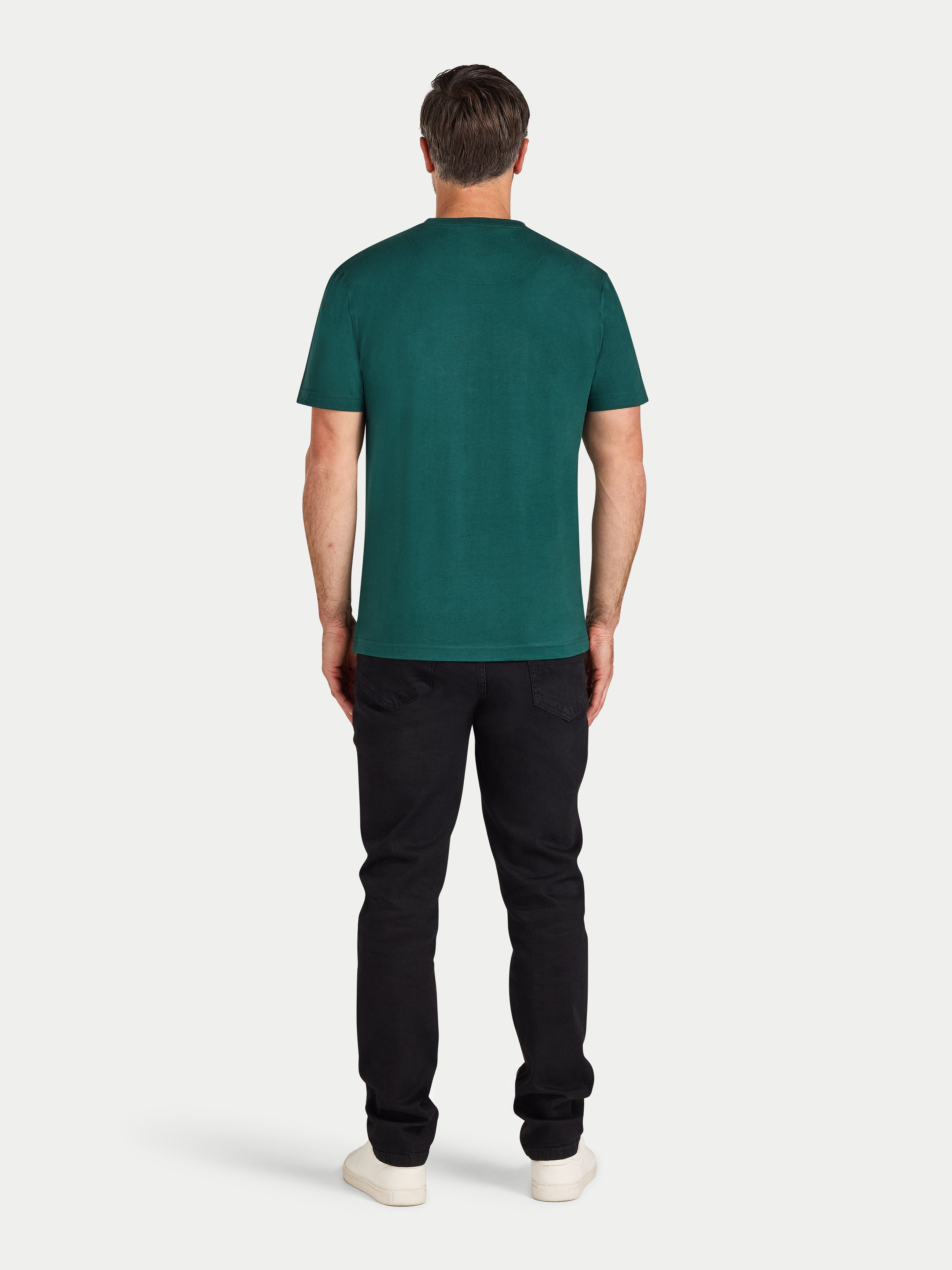 Man wearing a green t-shirt and black pants on a white background