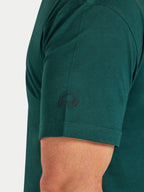 Green polo shirt with a logo on the chest area against a white background