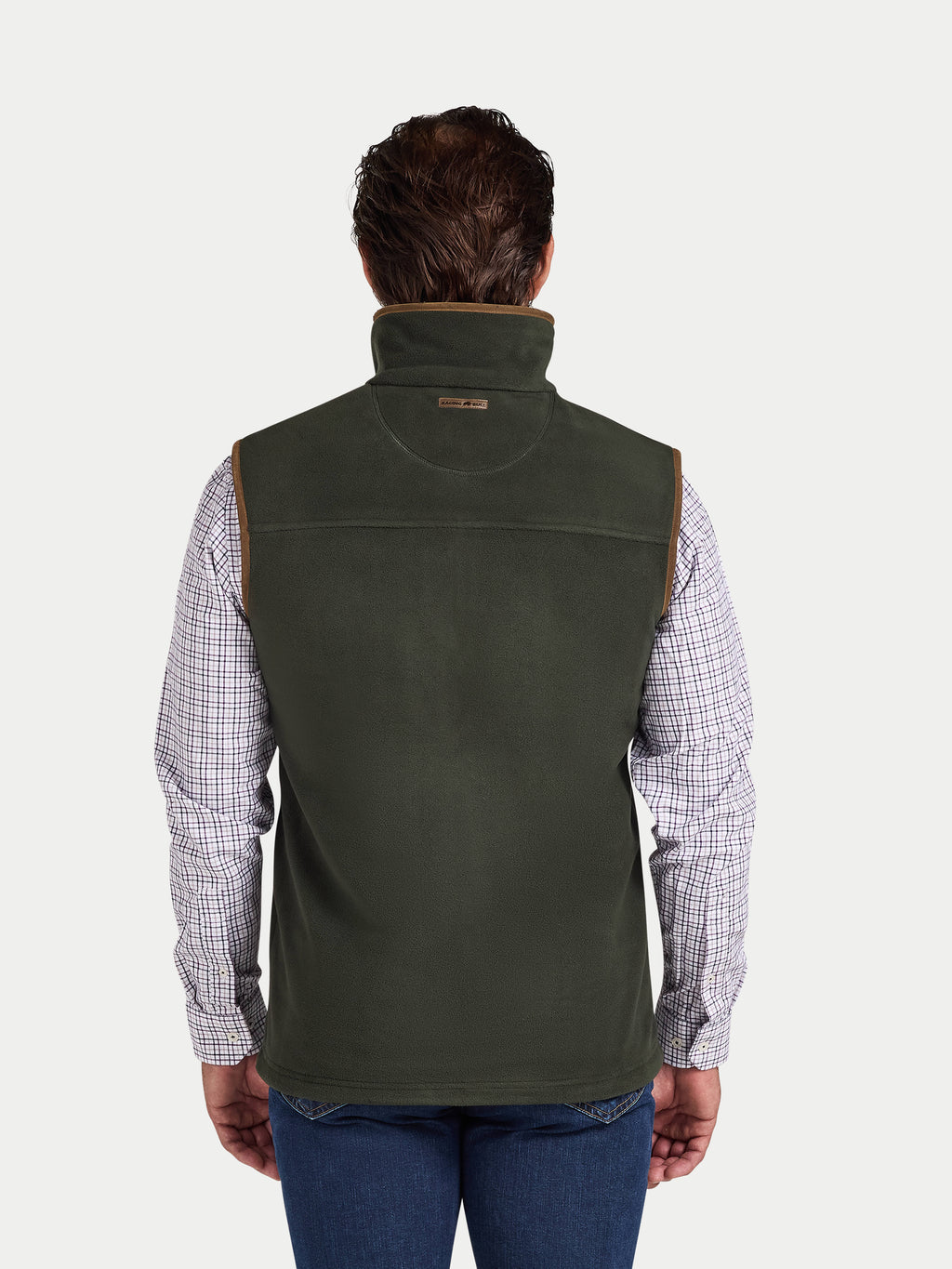 Man wearing a green vest over a plaid shirt on a white background