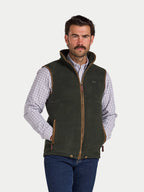 Man wearing a green vest over a plaid shirt on a white background