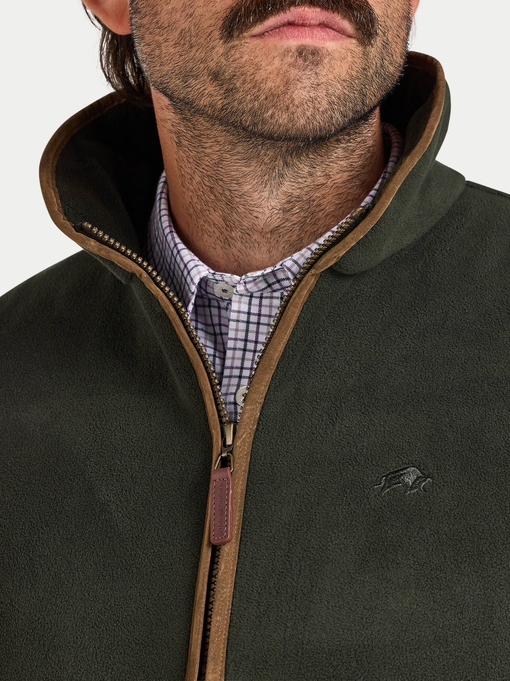 Close-up of a person wearing a green fleece gilet with a brand logo on a neutral background
