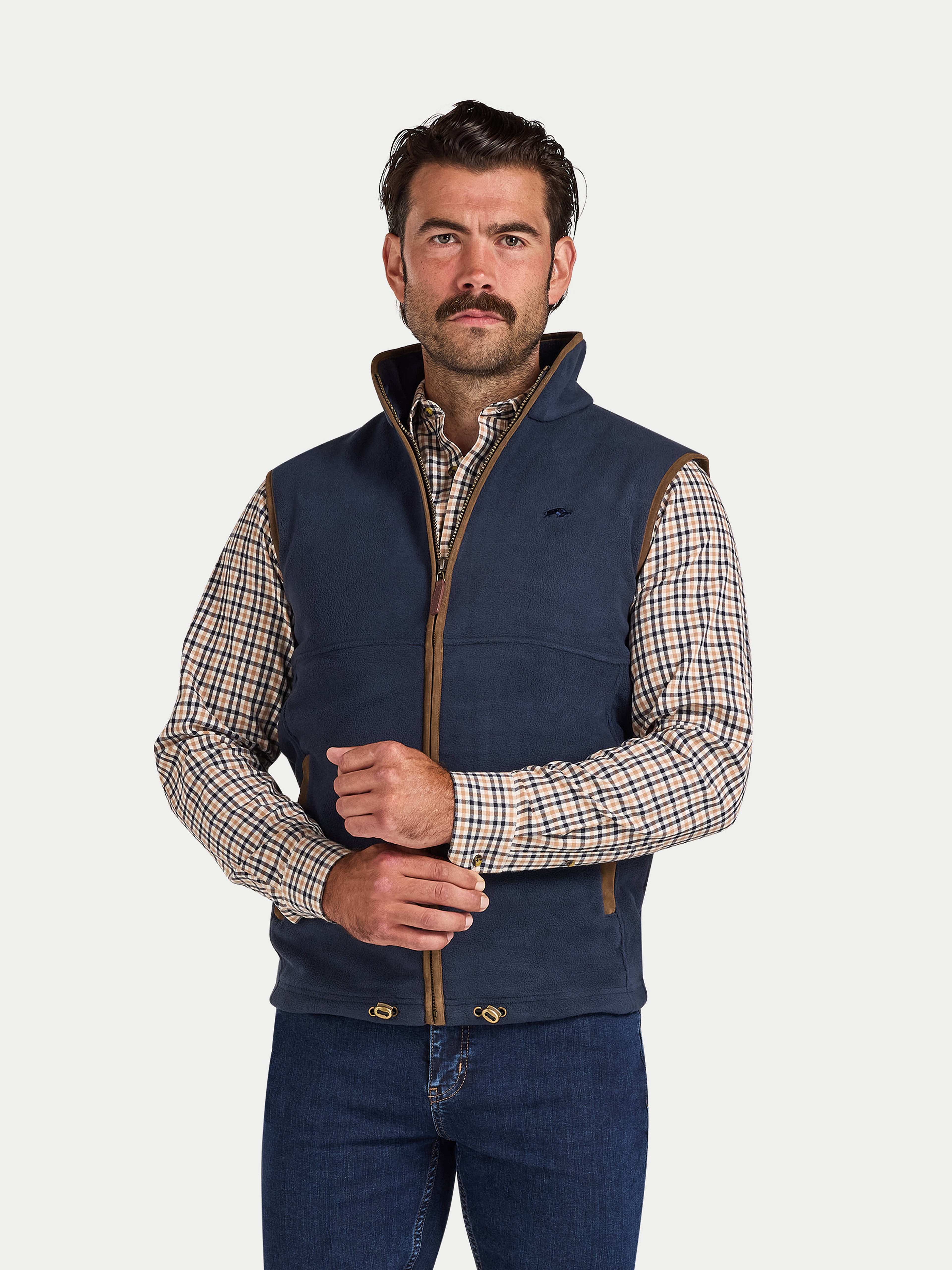 Man wearing a navy blue fleece vest over a plaid shirt on a white background