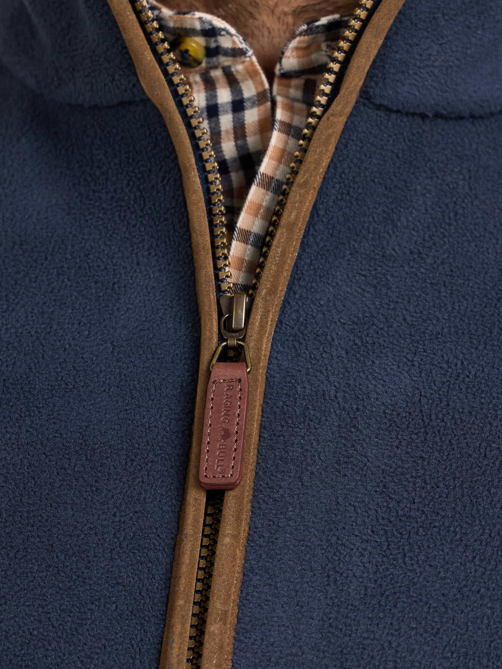 Close-up of a navy blue fleece gilet with a brown zipper and plaid lining.