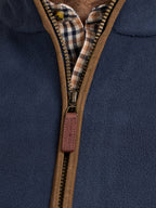 Close-up of a navy blue fleece gilet with a brown zipper and plaid lining.