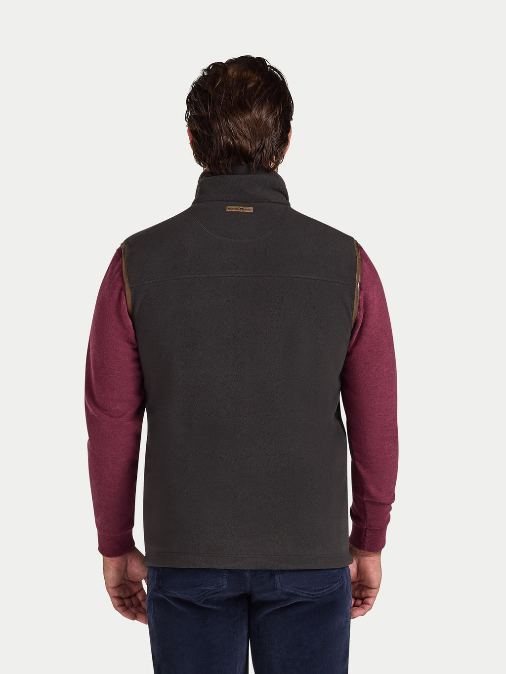 Man wearing a slate coloured gilet over a burgundy shirt on a white background