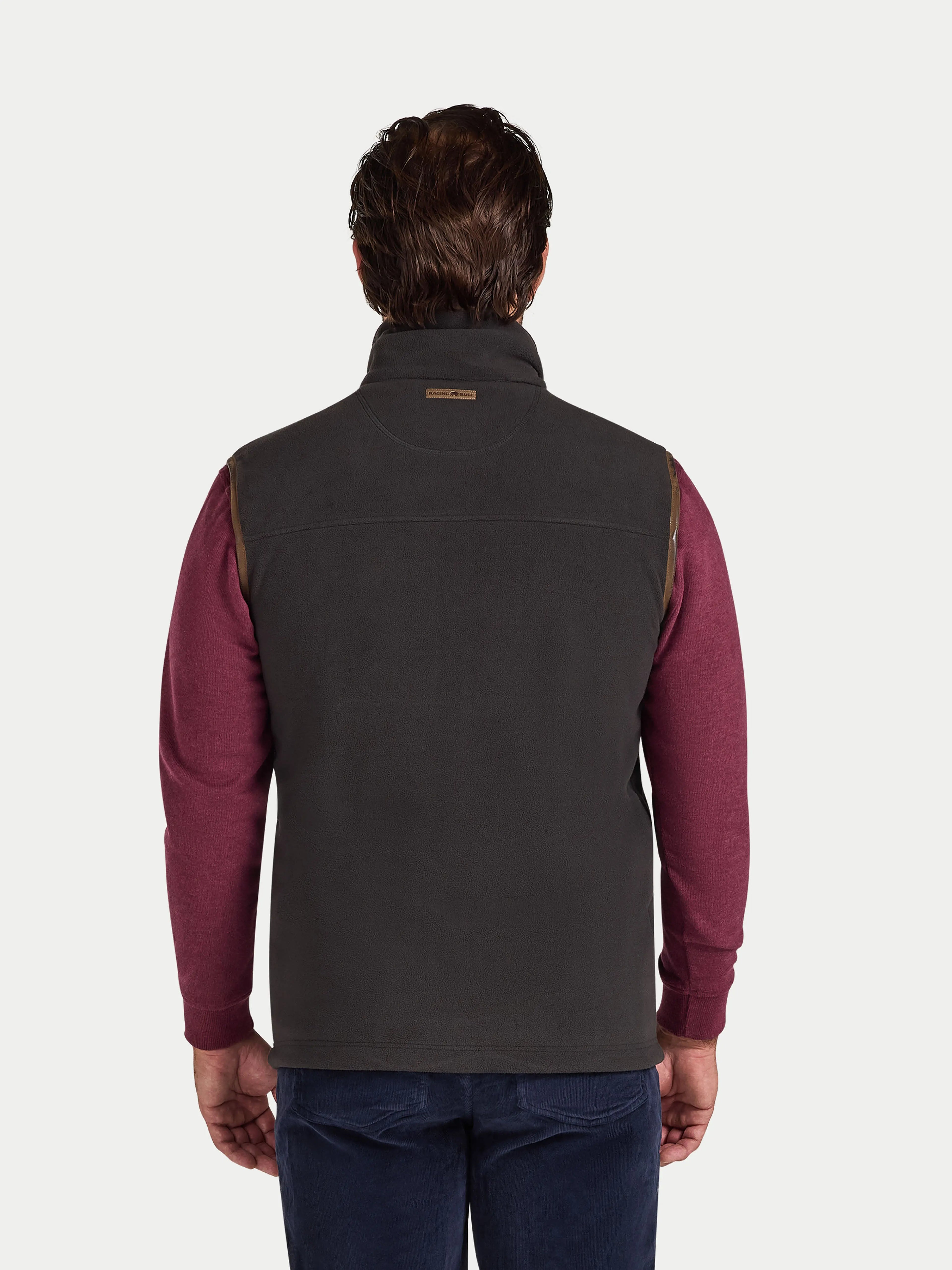 Man wearing a slate coloured gilet over a burgundy shirt on a white background