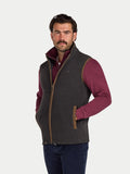 Man wearing a dark gray gilet over a maroon shirt on a white background