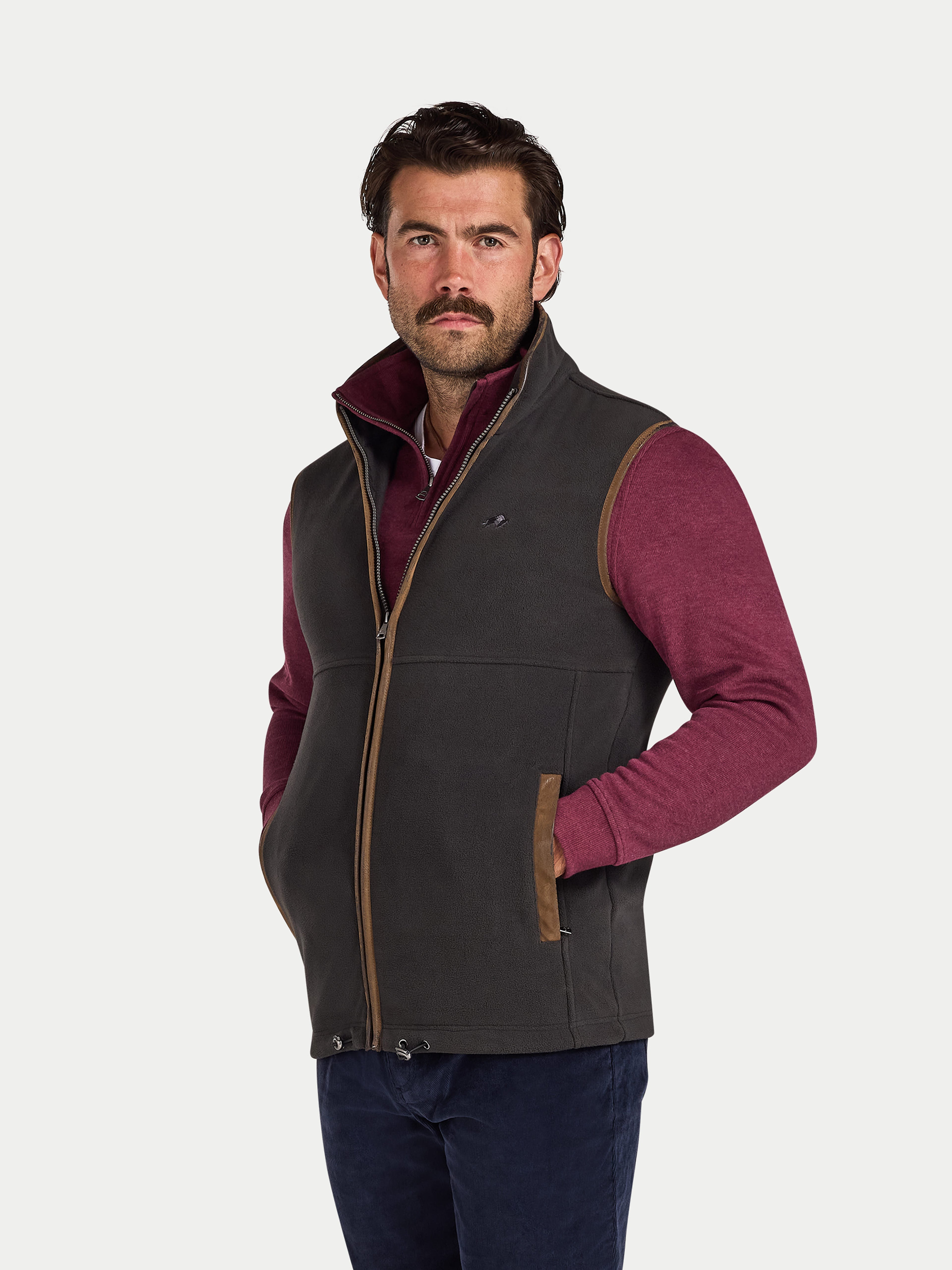 Man wearing a dark gray gilet over a maroon shirt on a white background