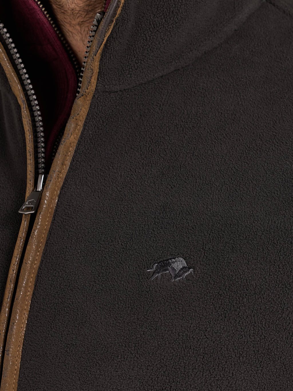 Close-up of a dark jacket with a zipper and Raging Bull logo.