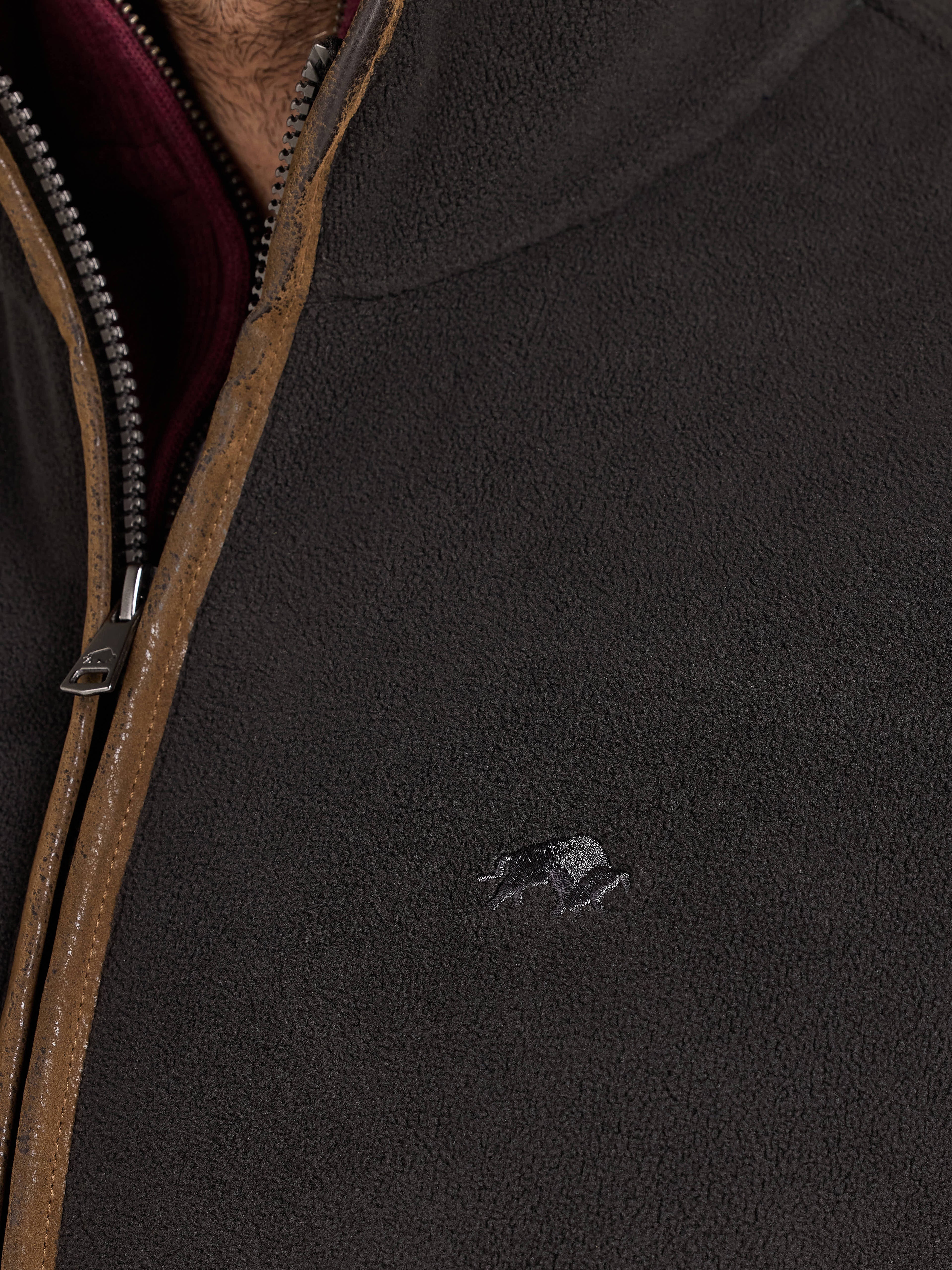 Close-up of a dark jacket with a zipper and Raging Bull logo.