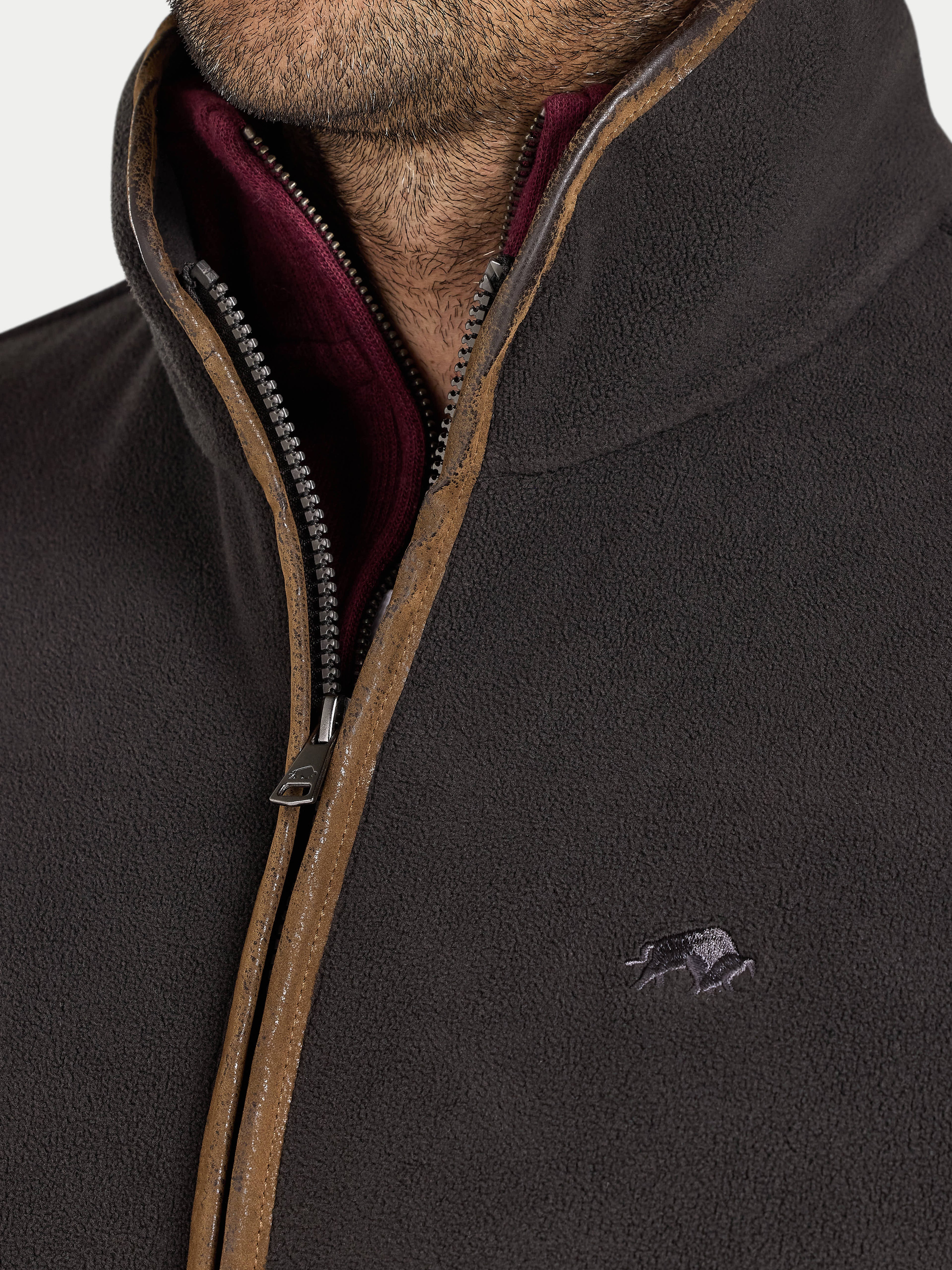 Close-up of a slate coloured fleece gilet with a zipper and brand logo.