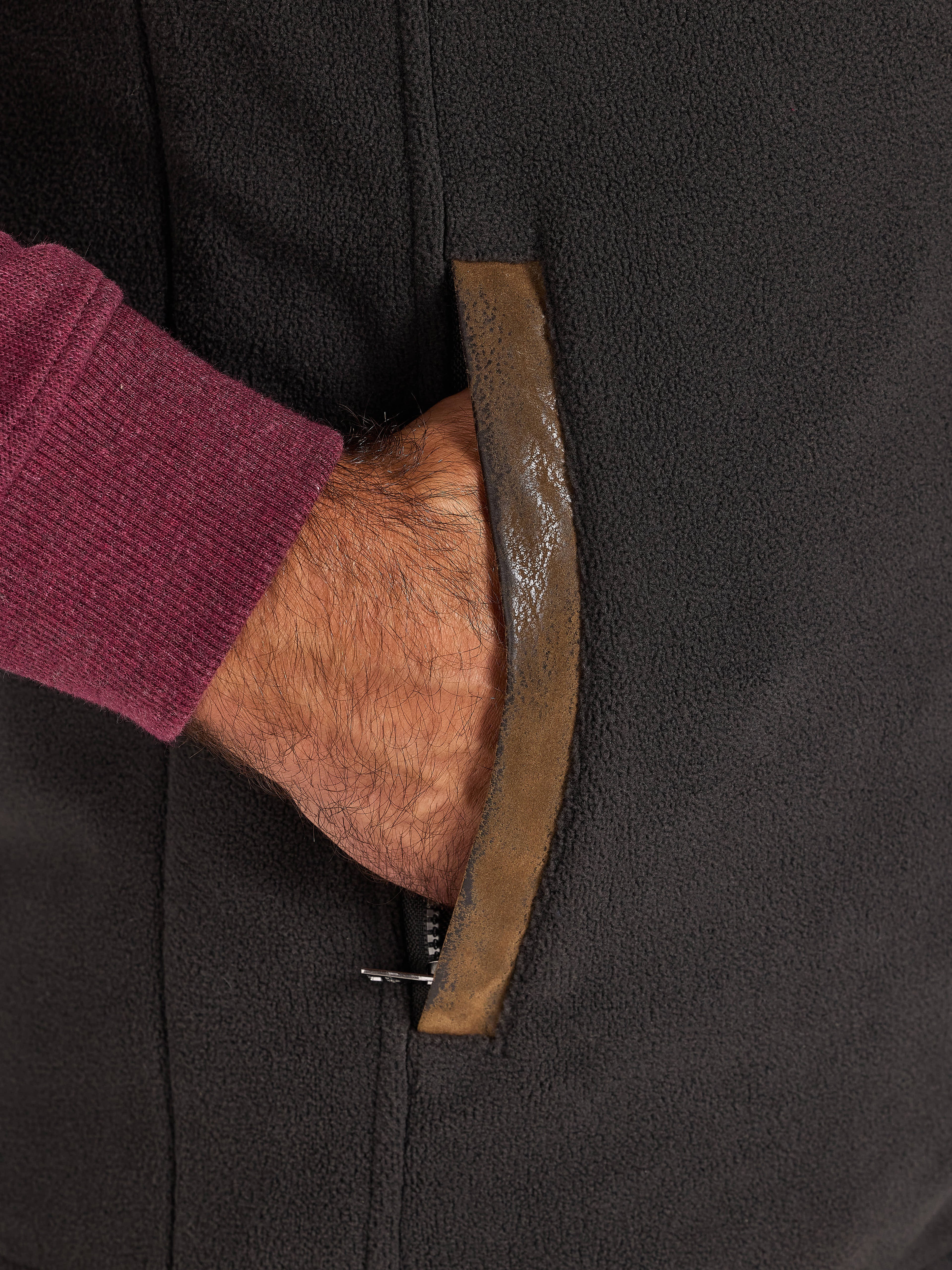 Close-up off a hand in a pocket of a slate coloured gilet.