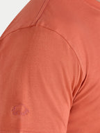Close-up of a rust-colored shirt with a logo on the chest.