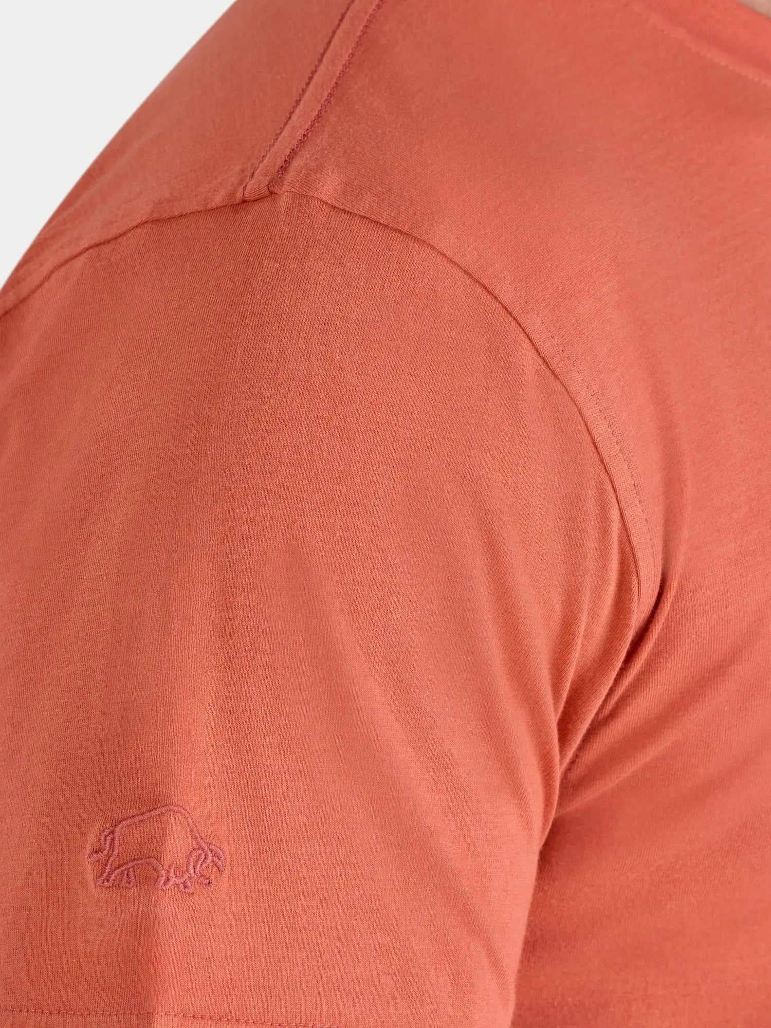 Close-up of a rust-colored shirt with a logo on the chest.