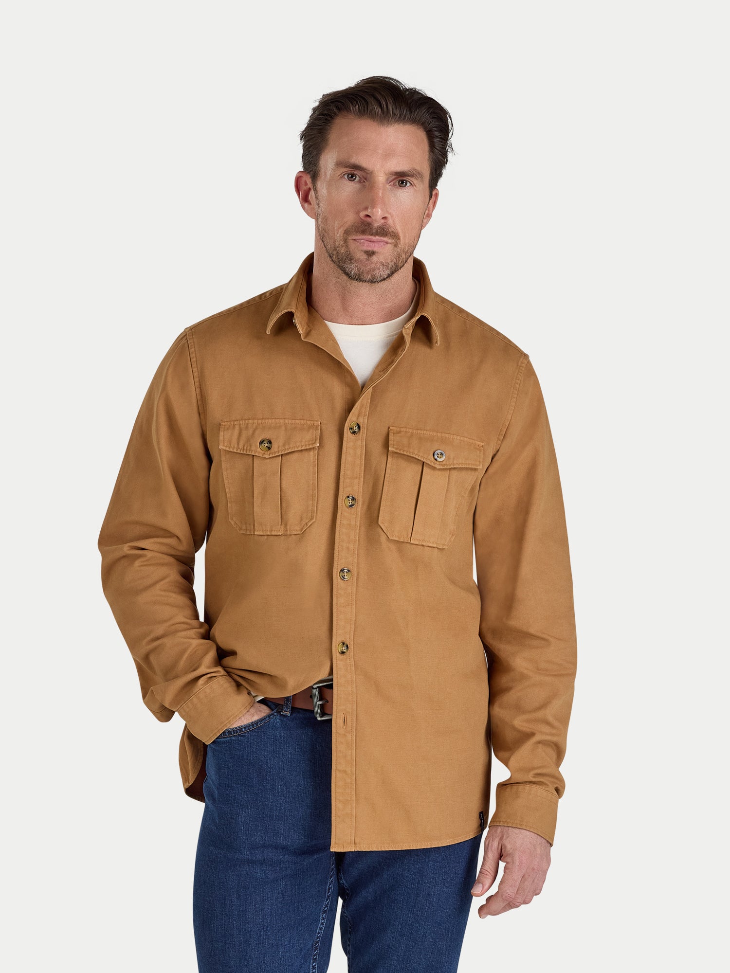 Man wearing a brown shirt with two front pockets on a white background