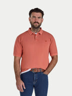 Man wearing an orange polo shirt and blue jeans on a white background