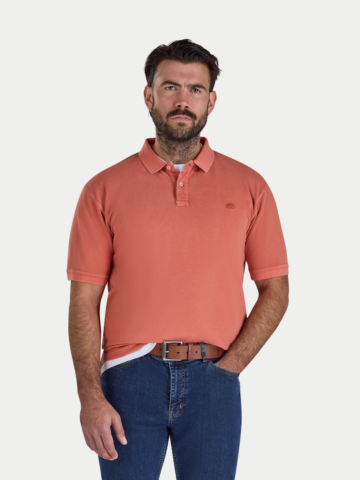 Man wearing an orange polo shirt and blue jeans on a white background