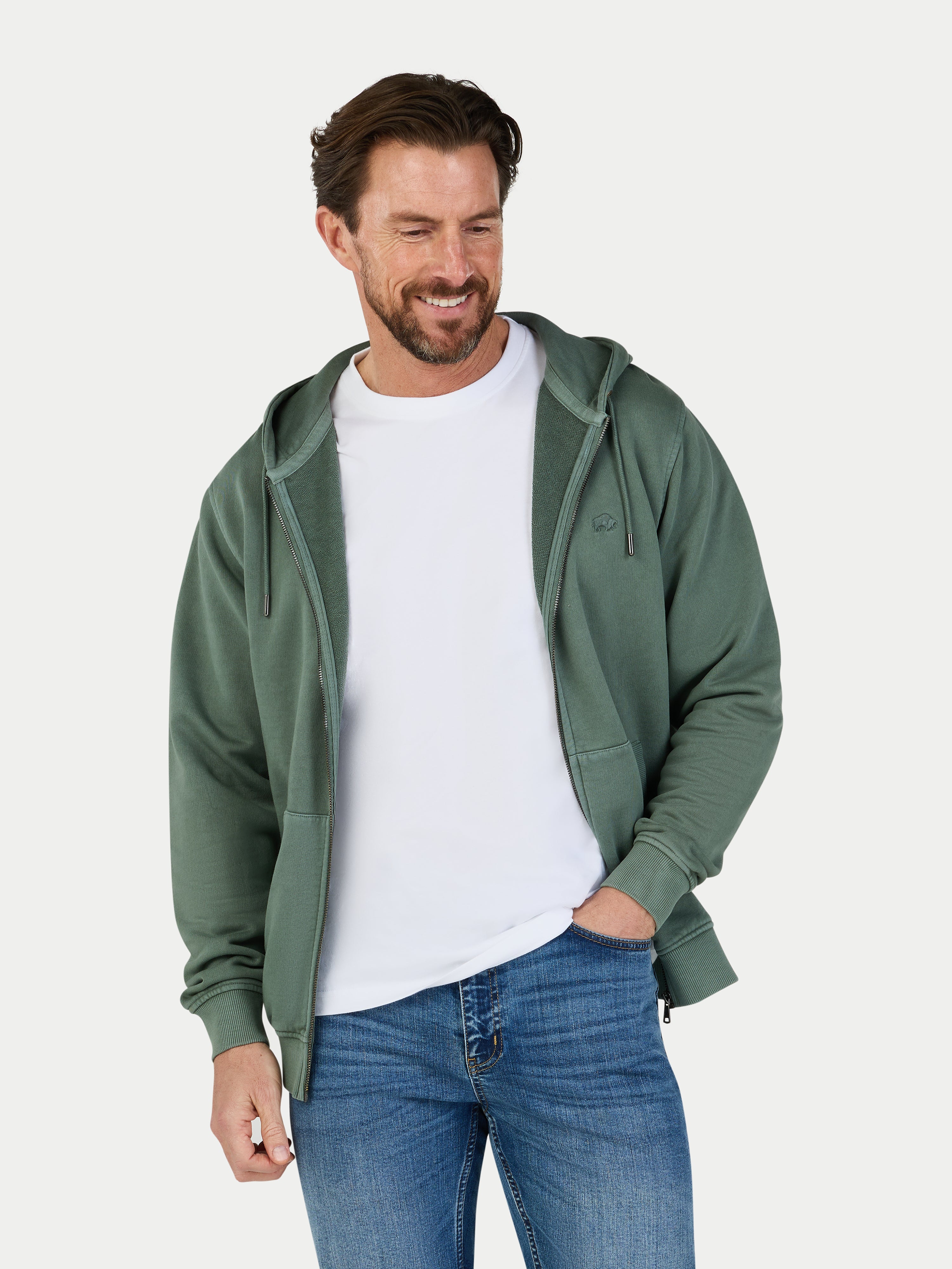 Man wearing a green hoodie, white t-shirt, and blue jeans on a light gray background