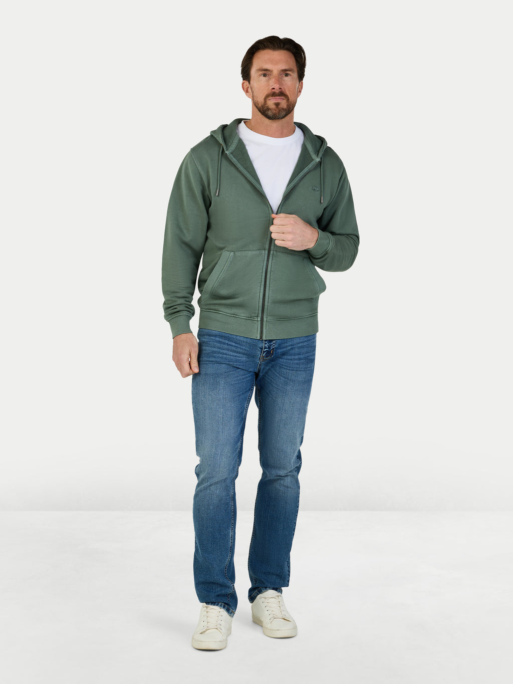 Man wearing a green hoodie and blue jeans on a white background
